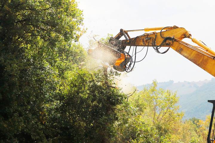 FEMAC hydraulic mulcher on an excavator clearing brush on a hillside